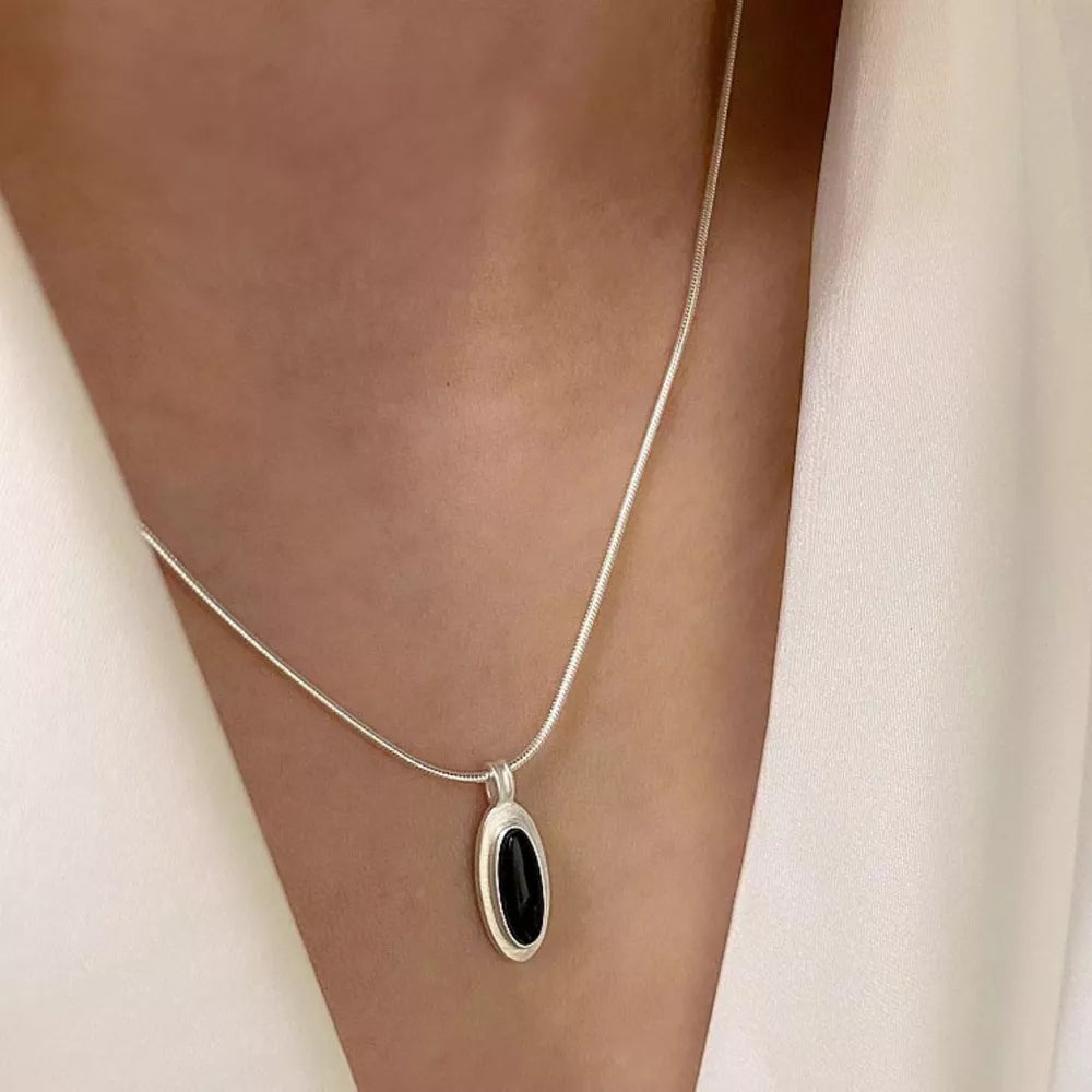Geometric agate pendant necklace in silver with black stone detail.