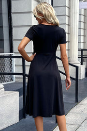 Black midi dress with short sleeves, button front, and a slit detail.