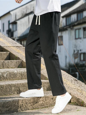 Black drawstring sweatpants with pockets on a man walking on stone stairs.
