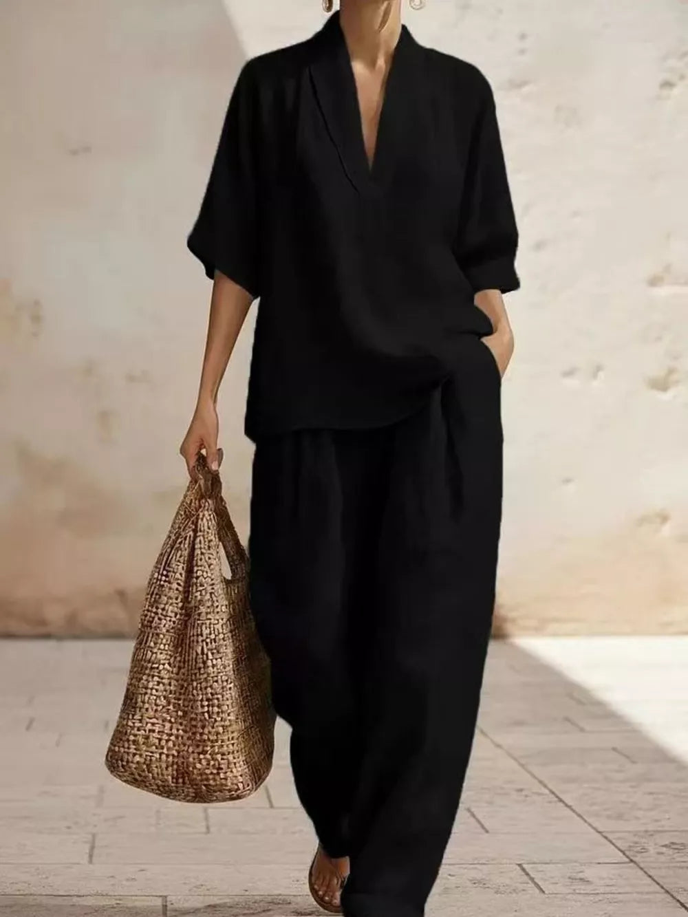 Black half-sleeve top with V-neck and wide-leg pants set, styled with a straw bag.