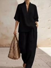 Black half-sleeve top with V-neck and wide-leg pants set, styled with a straw bag.