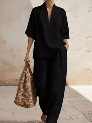 Black half-sleeve top with V-neck and wide-leg pants set, styled with a straw bag.