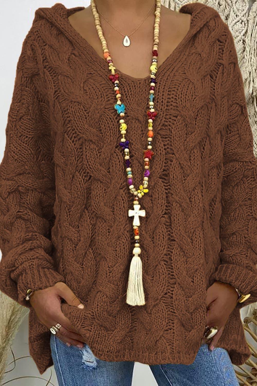 Brown cable knit hooded sweater with a V-neck and relaxed cocoon fit.