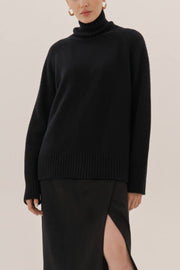 Black cashmere turtleneck sweater with raglan sleeves and ribbed trim.