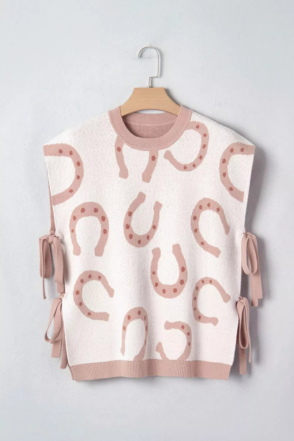 White knit tank top with pink horseshoe pattern and side ties.