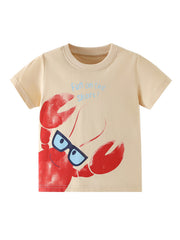 Beige cotton toddler tee with a playful red lobster graphic wearing sunglasses and blue text that says "Fun on the shore!".