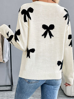 Cream knit crewneck sweater with scattered black bow pattern.