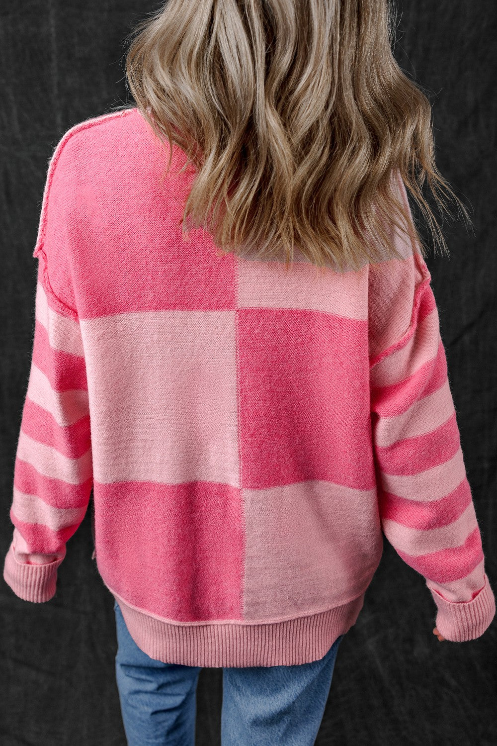 Checkerboard knit crewneck sweater in blush pink with striped sleeves.