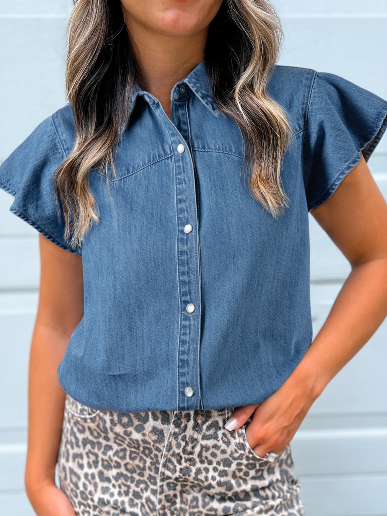 Ruffled denim button-up shirt with short flutter sleeves and pearl buttons.