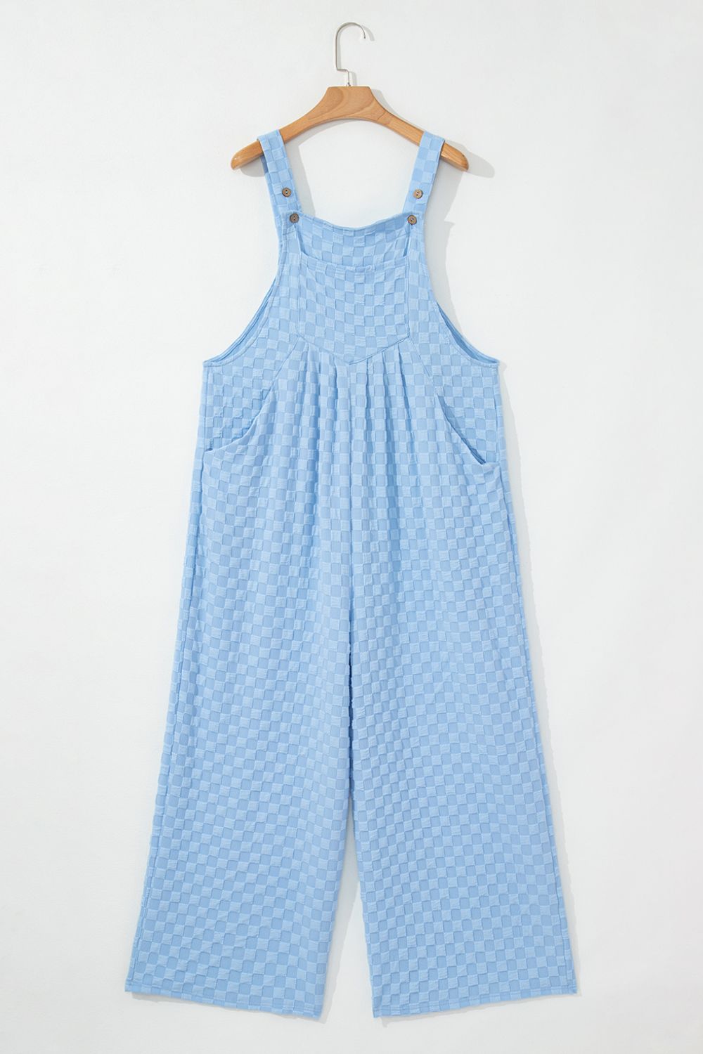 Light blue checkered textured jumpsuit with button straps and wide legs.
