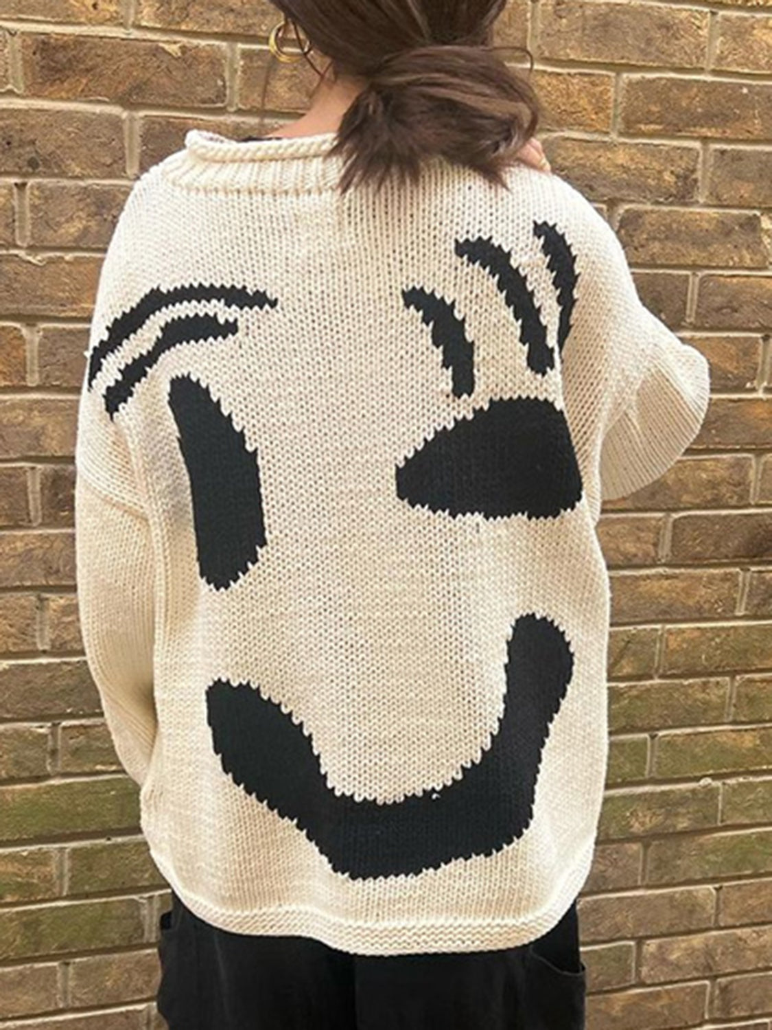 Cream graphic knit sweater with a playful black smiley face design on the back.