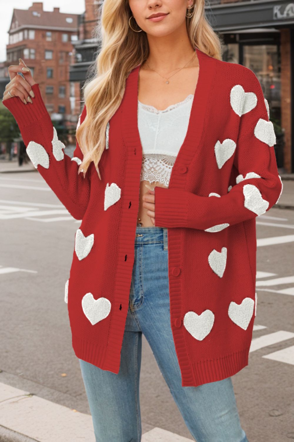 Red knit cardigan with white heart appliqués, button front, and ribbed cuffs.