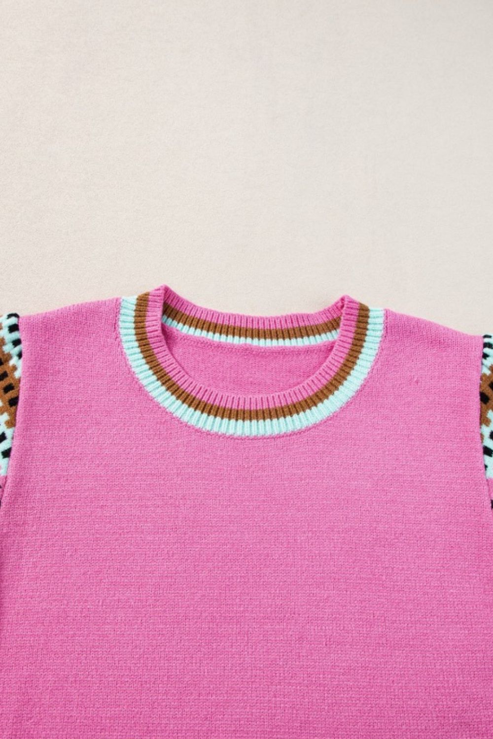 Fuchsia pink knit top with geometric patterned sleeves and striped neckline.