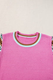Fuchsia pink knit top with geometric patterned sleeves and striped neckline.
