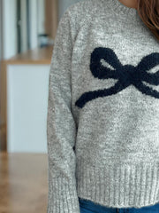 Gray knit sweater with intarsia bow design and crew neck.