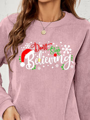 Dusty Pink corduroy crewneck sweatshirt with "Don't Stop Believing" Christmas graphic and Santa hat detail.