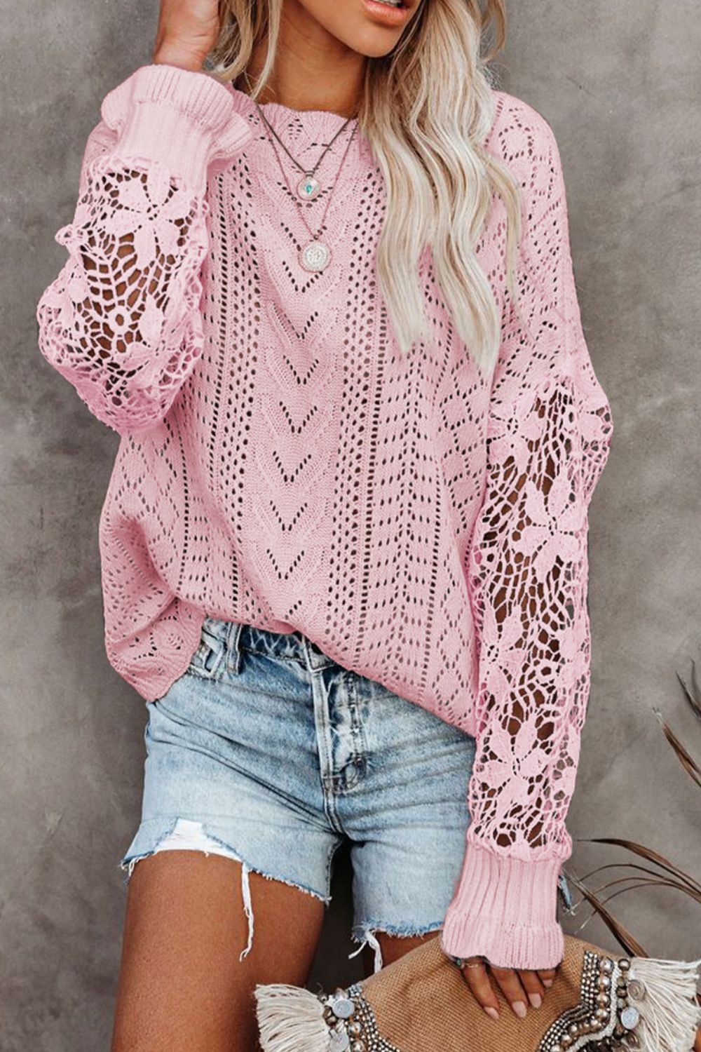 Pink openwork knit sweater with lace sleeves and chevron pattern.