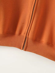 Orange zip-up top with ribbed hem detail and side zipper accent.