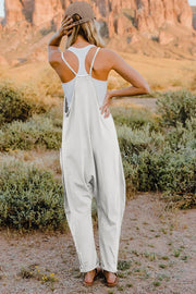 White cotton wide-leg jumpsuit with pockets and V-neck, styled with a tank top.