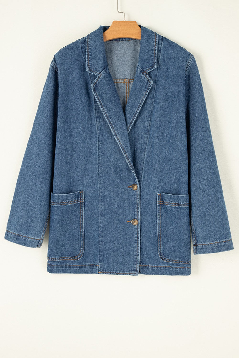 Medium wash denim double-breasted blazer with two button closure and flap pockets.