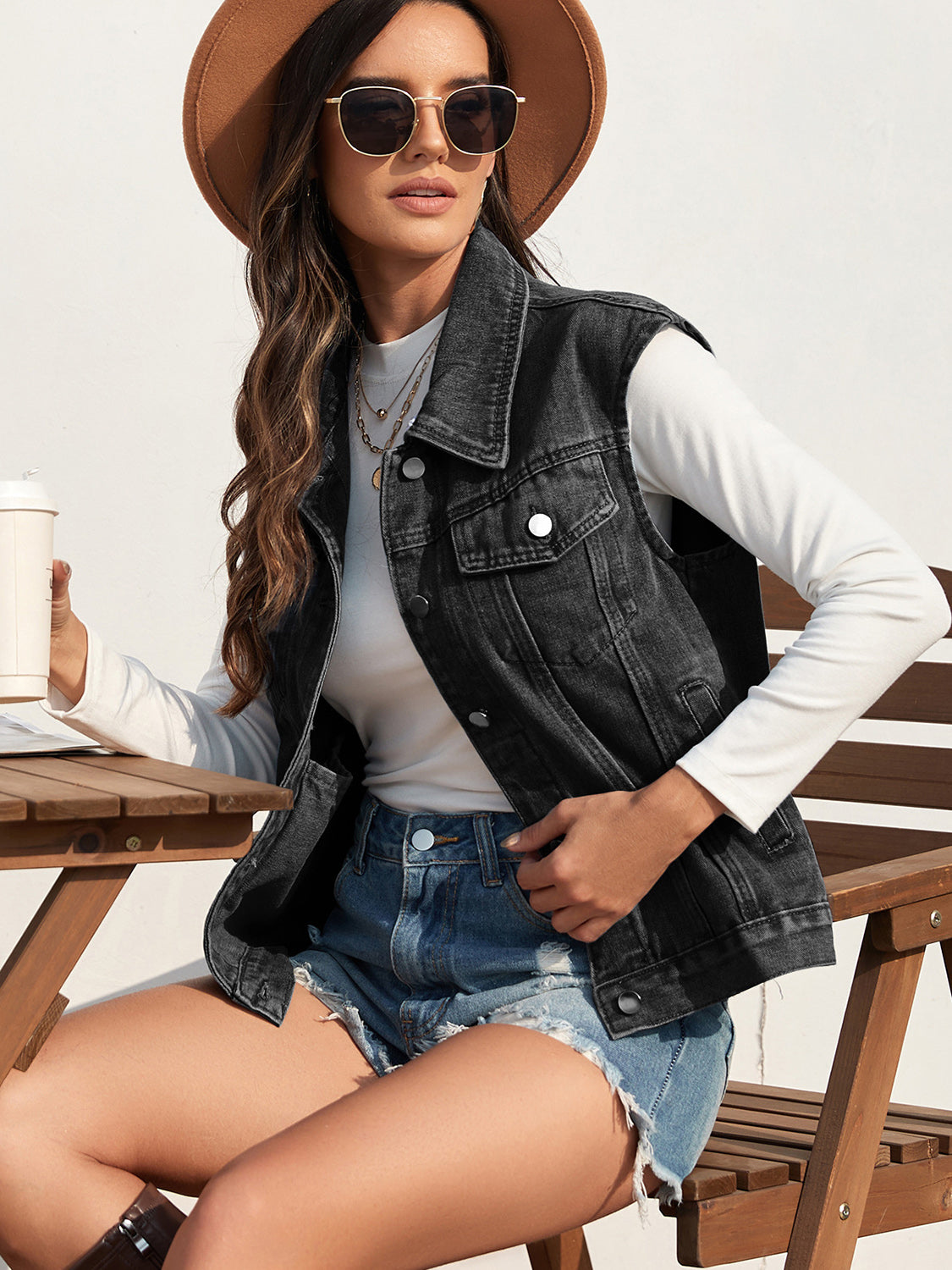 Washed black denim vest with collar and patch pockets, worn by a woman.