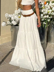 White tiered maxi skirt with smocked waist and crinkled texture, styled with a brown belt.
