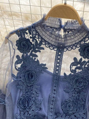 Blue embroidered lace blouse with floral appliques and a ruffled mock neck over a cami.