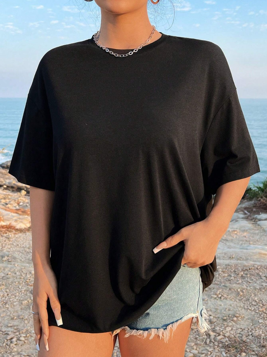 Black oversized graphic tee with crew neck and short sleeves, made of 100% polyester.