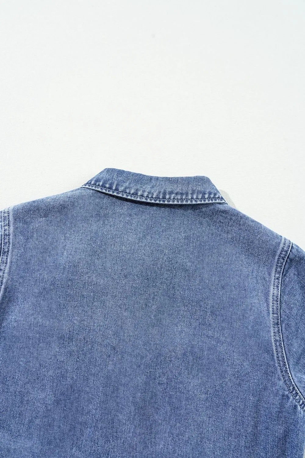 Medium wash denim romper with button-down collar and elastic waist detail.
