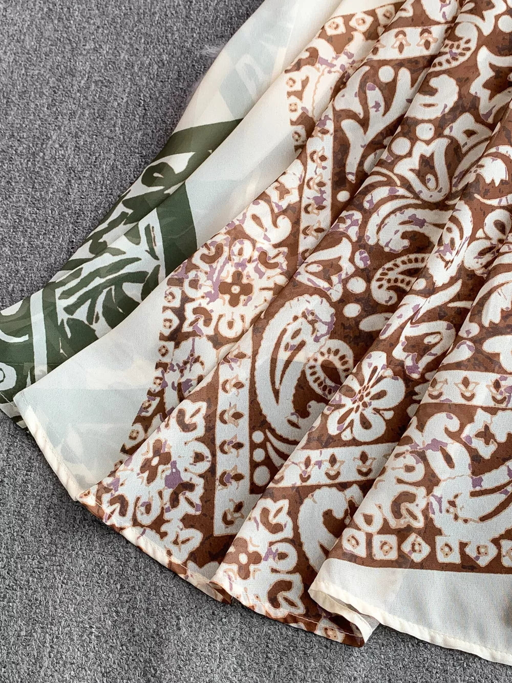 Dual-pattern V-neck cami dress with brown and white paisley print and green abstract pattern.
