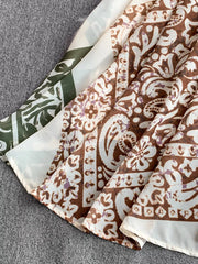 Dual-pattern V-neck cami dress with brown and white paisley print and green abstract pattern.