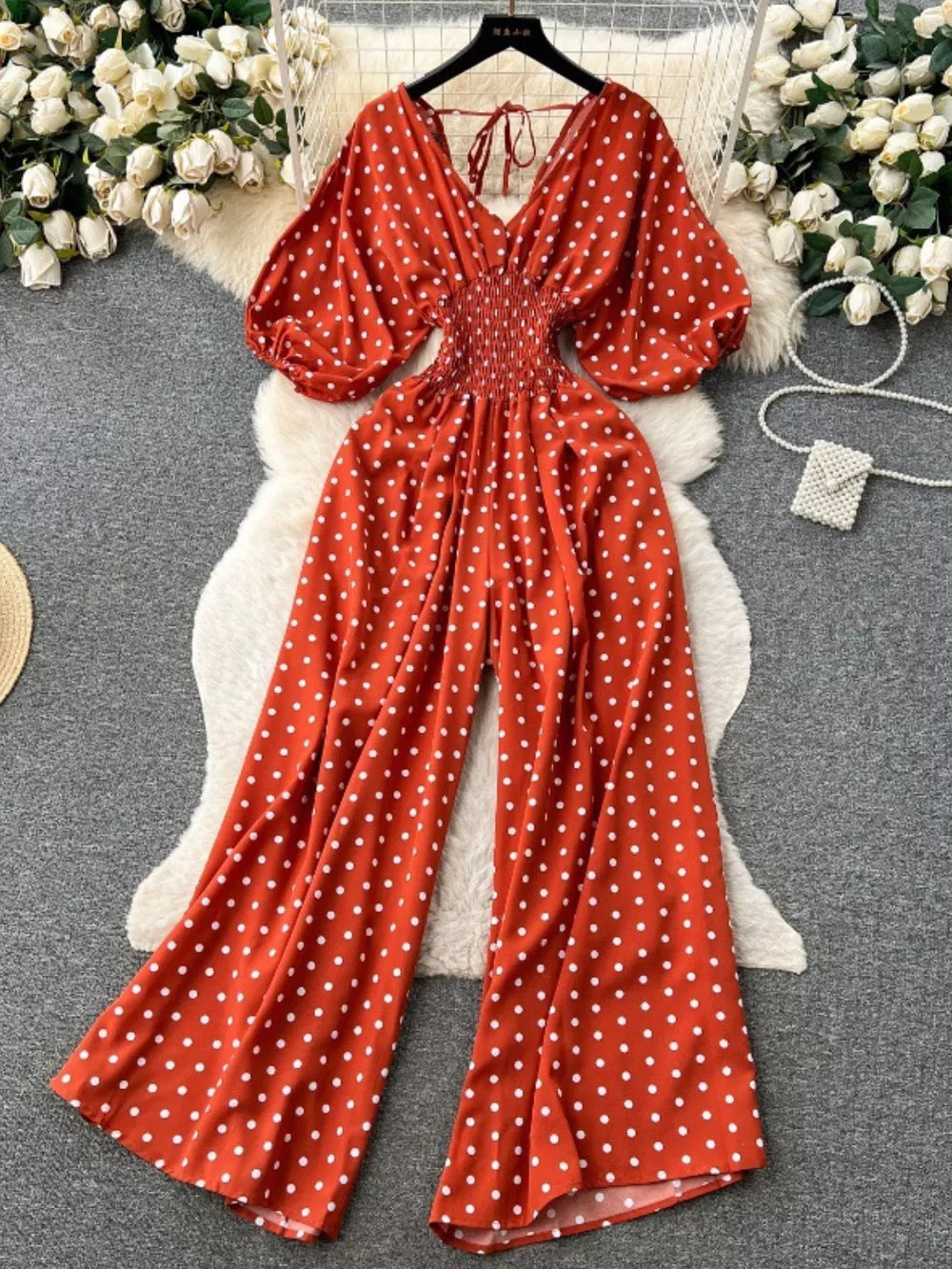 Scarlet polka dot smocked wide-leg romper with V-neck and puff sleeves.