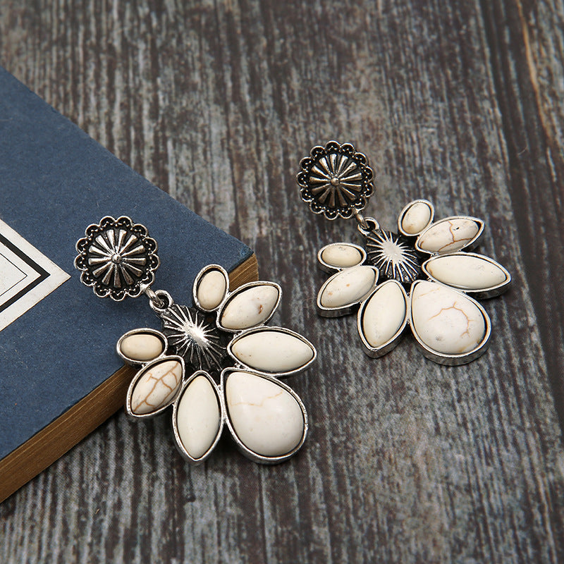 White petal drop earrings with silver floral accents and stone details.