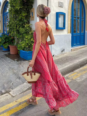 Backless maxi dress with deep rose paisley print, halter neck, and tiered skirt.