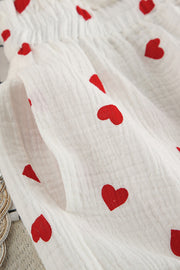 White gauze pajama set with red heart print, showing texture and pocket detail.