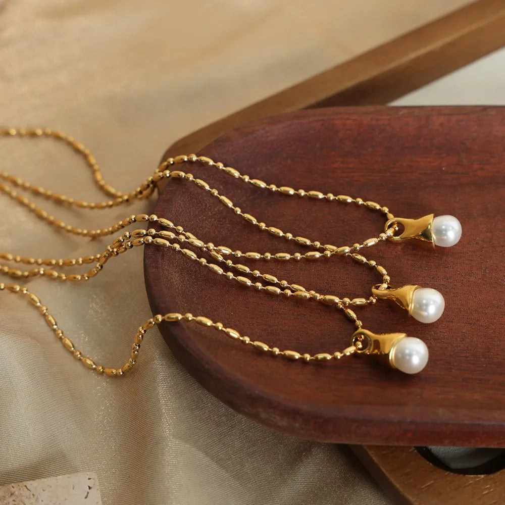 Gold pearl drop necklace with a bead chain and elegant pendant.