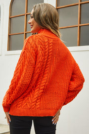 Orange cable-knit turtleneck sweater with voluminous silhouette and textured acrylic knit.