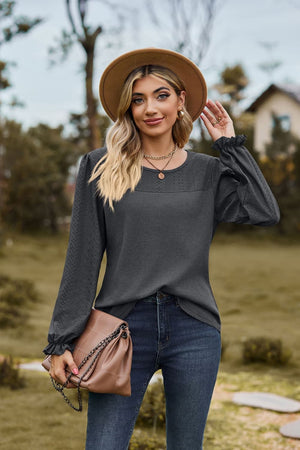 Dark gray waffle knit blouse with perforated yoke and ruffled cuffs.