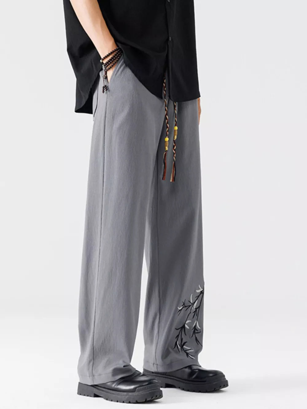 Men's light gray wide-leg sweatpants with embroidered branch detail and drawstring waist.