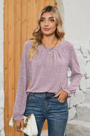 Lilac knit top with pleated yoke and ruffled cuffs, round neck, long sleeves.