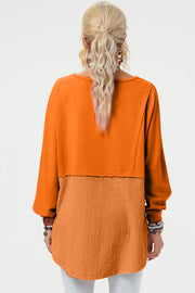 Tangerine sweatshirt with split panel design and asymmetric hemline.