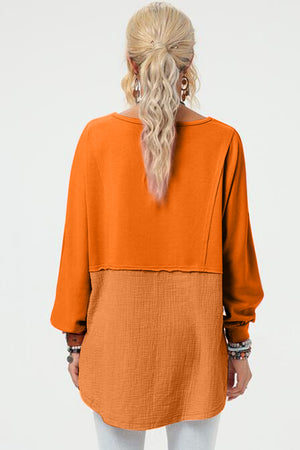 Tangerine sweatshirt with split panel design and asymmetric hemline.