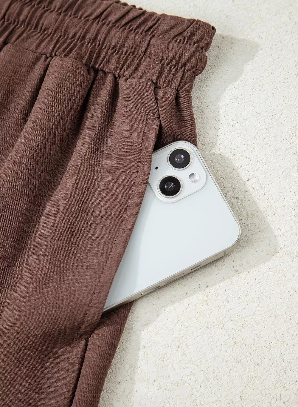 Brown maternity trousers with drawstring detail and a phone in the pocket.