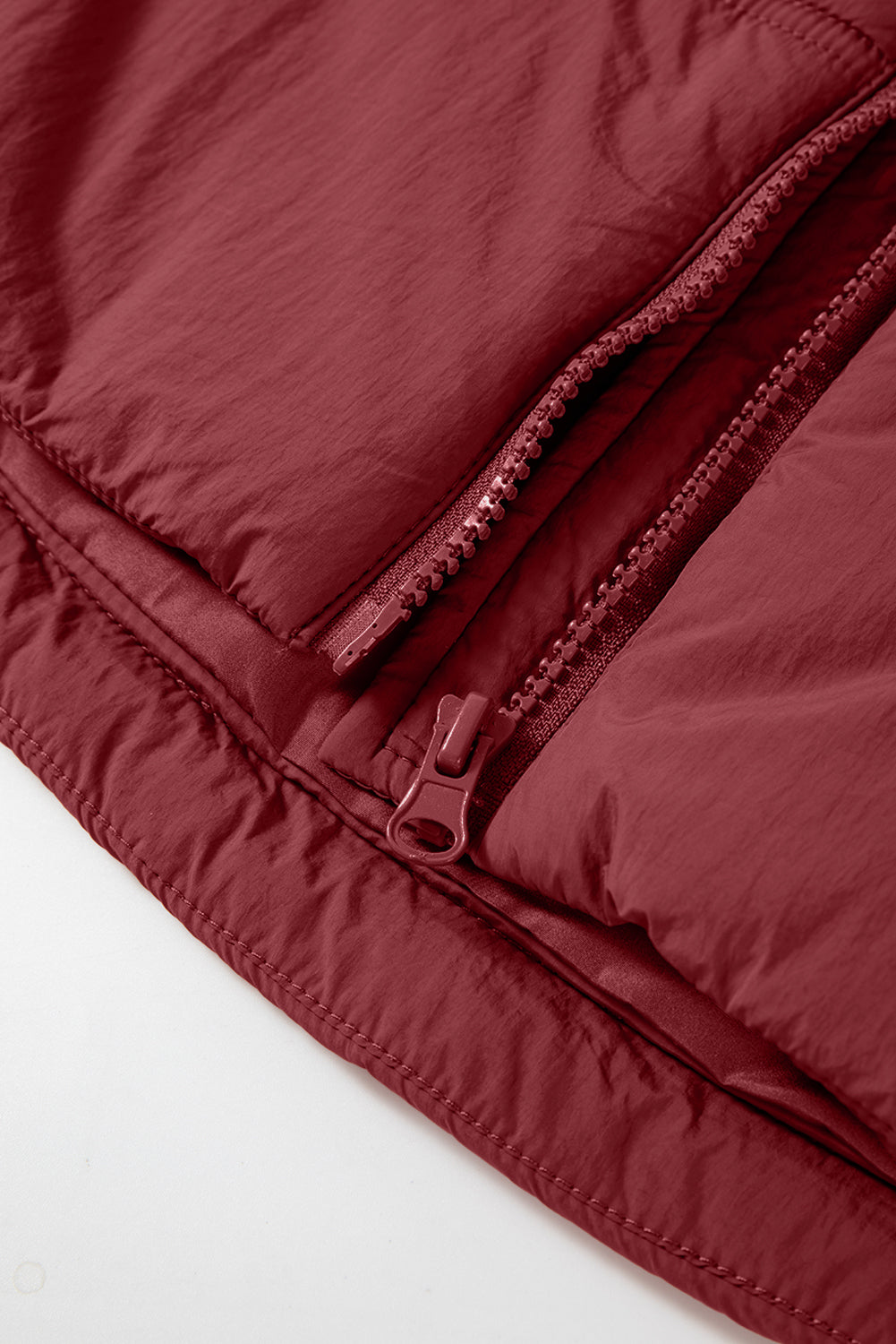 Burgundy quilted puffer vest detail with zippers and stitching