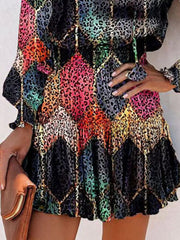 Abstract leopard print tiered mini dress with ruffles and gold chain detail.