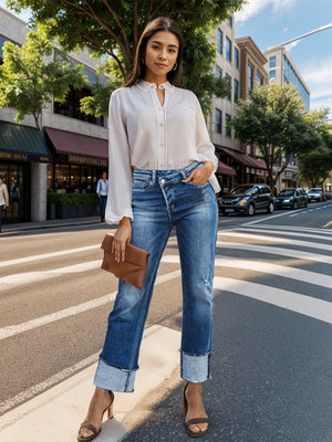 Medium wash cotton jeans with asymmetric waist, button fly, distressed details, and cuffed hems.