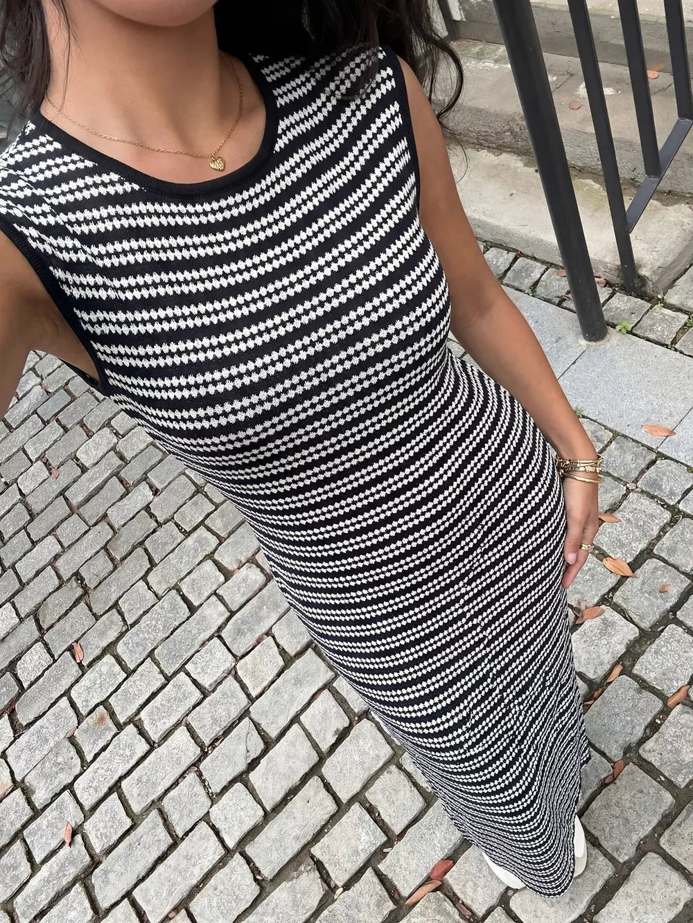 Sleek black and white striped knit maxi dress with a sleeveless, bodycon fit.