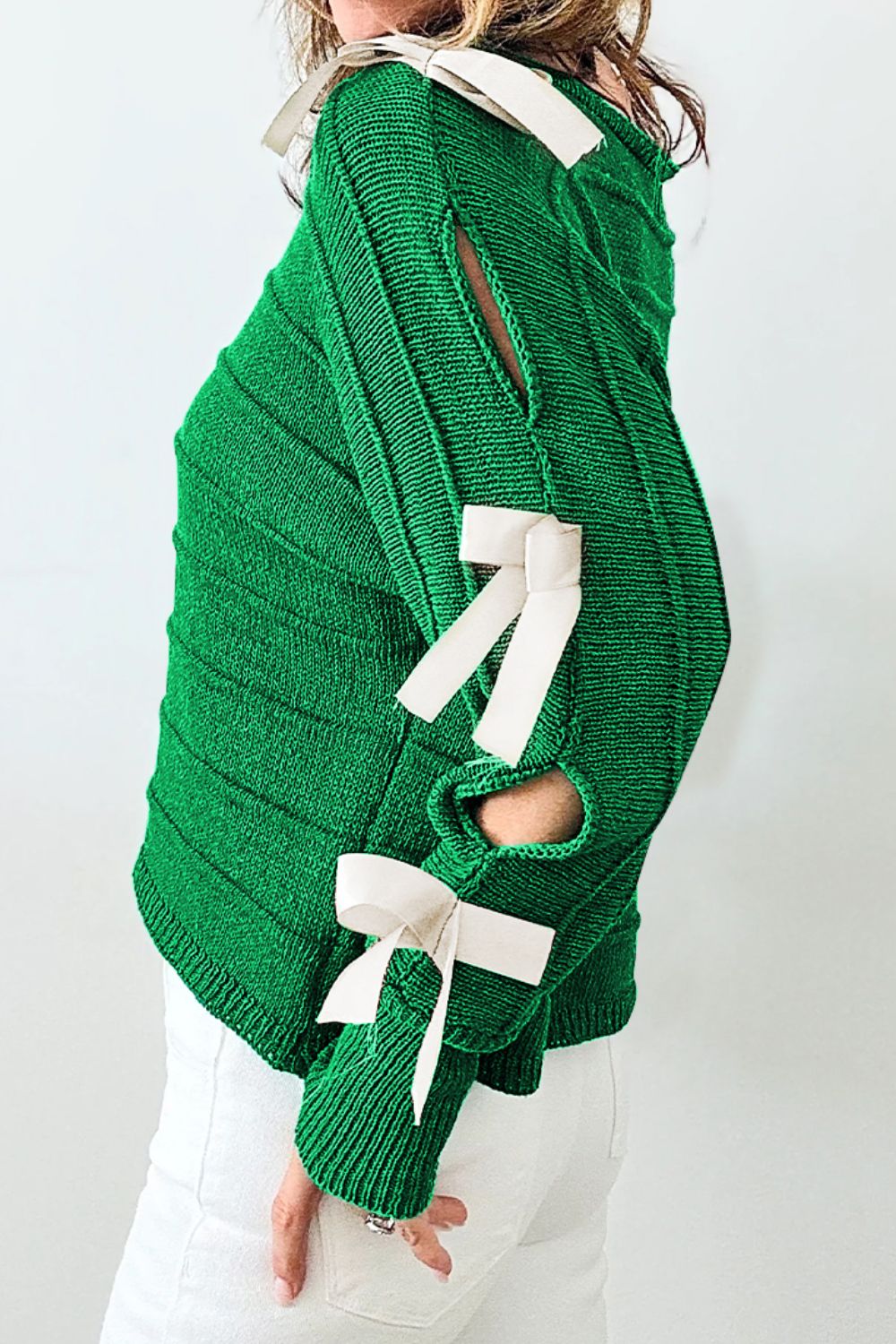 Green ribbed knit sweater with bow sleeve detail and cutouts.