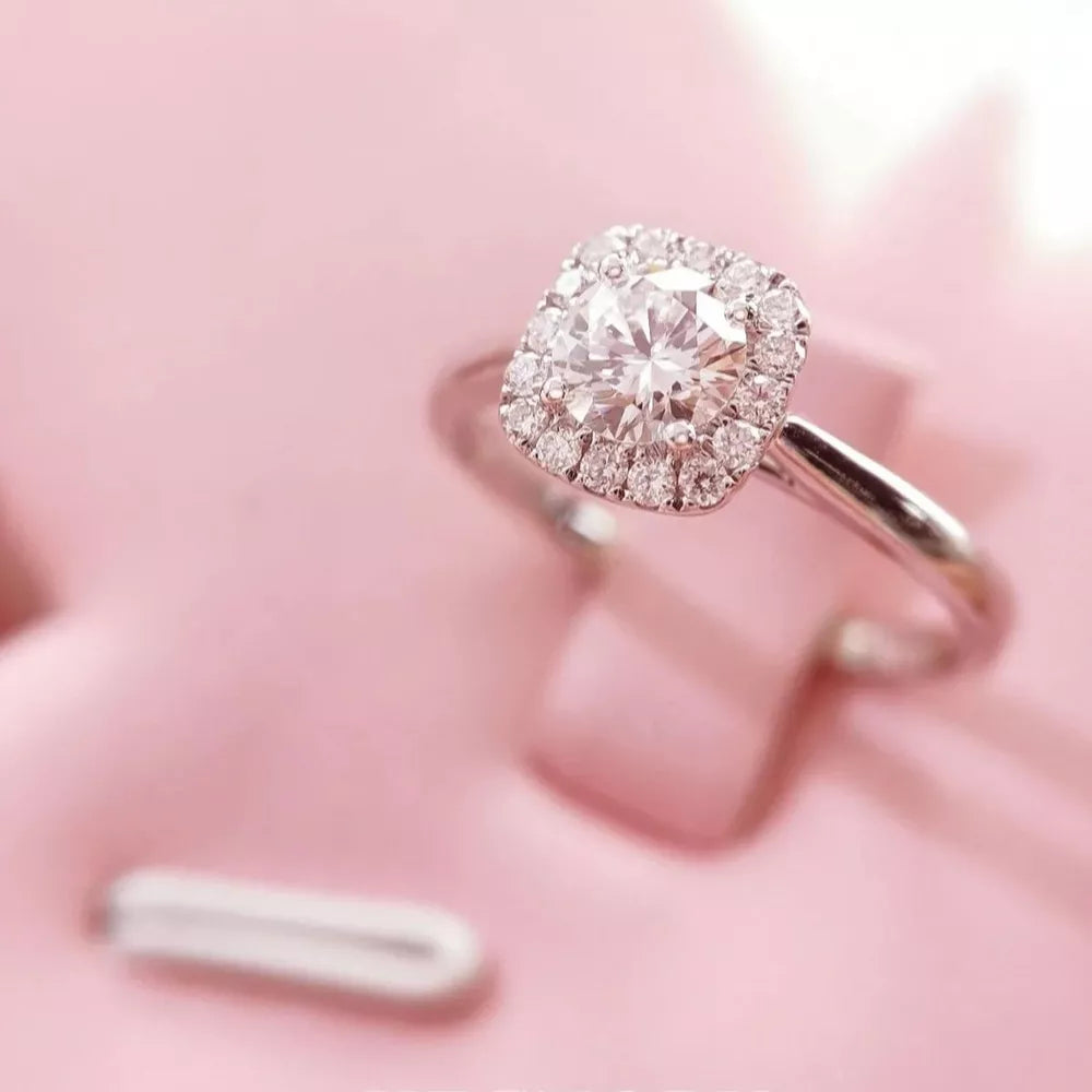 Elegant moissanite and sterling silver ring with cushion-cut center stone and halo.