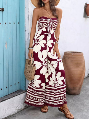 Burgundy floral tie-front strapless wide-leg romper with white print and patterned trim.